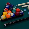 A rack of billiard balls on a green felt table, with two cue sticks and chalk cubes. Voir les images du produit