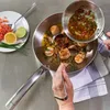 A person is cooking scallops in a pan, adding a sauce from a smaller pan. Podgląd zdjęcia produktu