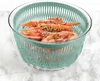A salad spinner filled with shrimp, placed on a marble countertop. Produktbild-Vorschau