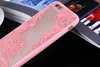 A close-up shot of a pink lace-designed phone case for an Apple iPhone SE 2020, placed on a dark surface with blurred background elements including magazines and a white cup. Produktbild-Vorschau