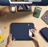 A top-down view of a desk with a laptop sleeve, a laptop, a calculator, and other office supplies. Produktbild-Vorschau