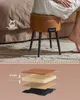 A person sitting on a round ottoman with storage, placed on a rug in front of a bed. Below is a layered diagram showing the construction of the ottoman's seat. A measurement indicator is shown for the seat thickness. Náhled obrázku produktu