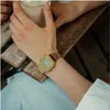 A person's wrist wearing a gold digital watch is shown, holding a drink. Produktbild-Vorschau