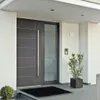 A modern front door with a side window, a doormat, and potted plants. Voir les images du produit