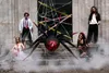 XXL Spinnen Folienballon in Schwarz und Rot als Halloween Dekoration mit Spinnennetz und verkleideten Personen. Produktbild-Vorschau