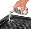 Eine Hand gießt Wasser aus einem Glaskrug in die dafür vorgesehene Öffnung des Unold 58565 Barbecue- Produktbild-Vorschau