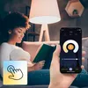 A woman is reading a book on a couch next to a lamp, while holding a smartphone that displays a lamp control app. Náhled obrázku produktu