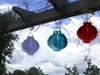 Three solar lanterns hanging from a wooden pergola against a cloudy sky. Podgląd zdjęcia produktu