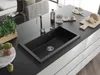 A modern kitchen island with a black granite sink, faucet, and various kitchen items like bread, cheese, and fruit. Produktbild-Vorschau