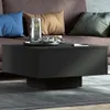 A black coffee table with a glass of water and other items on it, placed in a living room setting with a sofa and pillows in the background. Voir les images du produit
