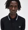 A close-up studio shot of a man wearing a black Fred Perry polo shirt. Produktbild-Vorschau