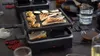 Auf dem ausziehbaren Raclette-Grill von Unold werden Brot, Garnelen, Zucchini und Pilze gegart, währ Produktbild-Vorschau