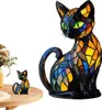 A stained glass cat figurine sits on a wooden table next to a vase of flowers. A larger stained glass cat lamp is also present. Produktbild-Vorschau