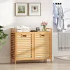 A bathroom scene with a bamboo laundry cabinet, folded clothes, and decorative items. Podgląd zdjęcia produktu