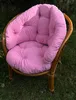A pink cushion set on a rattan garden chair outdoors. Produktbild-Vorschau