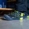 A person wearing safety shoes in what appears to be a warehouse or industrial setting. Produktbild-Vorschau