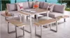 An outdoor lounge set with a sectional sofa, table, and benches, set on a patio with a view of water and trees. Produktbild-Vorschau