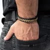 A man's hand with a bracelet is in the pocket of his jeans. Anteprima dell’immagine prodotto