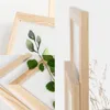 A close-up view of a wooden picture frame with a watercolor painting of leaves inside, and a real branch with leaves placed in front of it. Produktbild-Vorschau