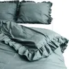 A close-up view of a teal-colored duvet cover and pillowcases with ruffled edges, laid out on a bed. Produktbild-Vorschau