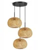 A three-light pendant lamp with woven bamboo shades hangs from a black ceiling mount. Náhled obrázku produktu