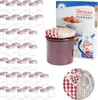 A collection of glass jars with red and white checkered lids, a jar filled with jam, and a recipe booklet. Produktbild-Vorschau