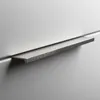 A close-up shot of a modern, brushed metal drawer pull on a light gray cabinet. Produktbild-Vorschau