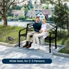 A couple sits on a park bench by a river with houses in the background. Produktbild-Vorschau