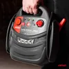 A person is holding a black jump starter device with red accents. Podgląd zdjęcia produktu