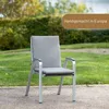 A gray garden chair with a cushion sits on a gravel path in a garden setting with green grass and trees in the background. Produktbild-Vorschau