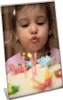 A young girl is blowing out candles on a birthday cake. Náhľad obrázku produktu