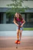 A young girl is jumping on a pogo stick outdoors. Produktbild-Vorschau
