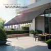 A modern outdoor patio with a retractable awning, dining table, and chairs, overlooking a city skyline. Náhled obrázku produktu