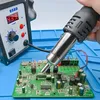 A hand holding a hot air soldering gun over a circuit board, with a soldering station in the background. Produktbild-Vorschau