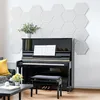 A piano with sheet music on it, a stool, and decorative items in a room with hexagonal wall panels. Produktbild-Vorschau