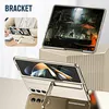 A collage of images showing a gold phone case with a built-in stand and pen holder, displayed on a desk and on a decorative stand. Produktbild-Vorschau