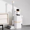 A white cordless vacuum cleaner with an auto-dust collection station is shown standing next to a white nightstand against a white wall. Produktbild-Vorschau