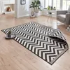 A chevron patterned rug is laid out on a wooden floor in a living room setting, with a corner folded over. Voir les images du produit