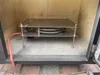 Inside a metal enclosure, a stainless steel rack holds coiled cables. An orange hose enters from the left. Náhled obrázku produktu
