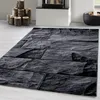 A rug with a stone pattern is placed on a light gray floor in front of a fireplace. Anteprima dell’immagine prodotto