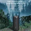 A black portable speaker is shown outdoors, surrounded by lush green foliage and a misty forest background. Produktbild-Vorschau