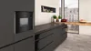 A modern kitchen counter with dark gray cabinets and a built-in black microwave. Náhľad obrázku produktu