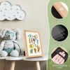 A children's picture frame with artwork inside, placed on a shelf next to a stuffed animal. The right side of the image shows close-ups of the frame's features. Produktbild-Vorschau