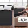 A split image showing a bed with a dark grey fitted sheet and white pillows on the left, and a hand stretching the fitted sheet over a mattress on the right, with text overlay. Produktbild-Vorschau