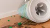 A cleaning roller is shown cleaning a wooden surface with green particles. Produktbild-Vorschau