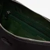 Close-up view of the interior of a black bag, showing the zipper and the green lining with the Lacoste logo repeated. Voir les images du produit