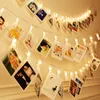 A string of fairy lights with photo clips, decorated with various photos, hanging on a wall. Produktbild-Vorschau