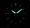 A close-up of a watch face in the dark, with luminous hands and markers. Produktbild-Vorschau
