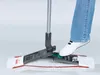 A person's leg is shown stepping on a mop head, demonstrating how to attach or detach it. Produktbild-Vorschau