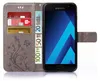A grey flip-style phone case with a floral pattern, showing credit cards and euro banknotes inserted into its compartments, and a Samsung smartphone placed inside. Produktbild-Vorschau